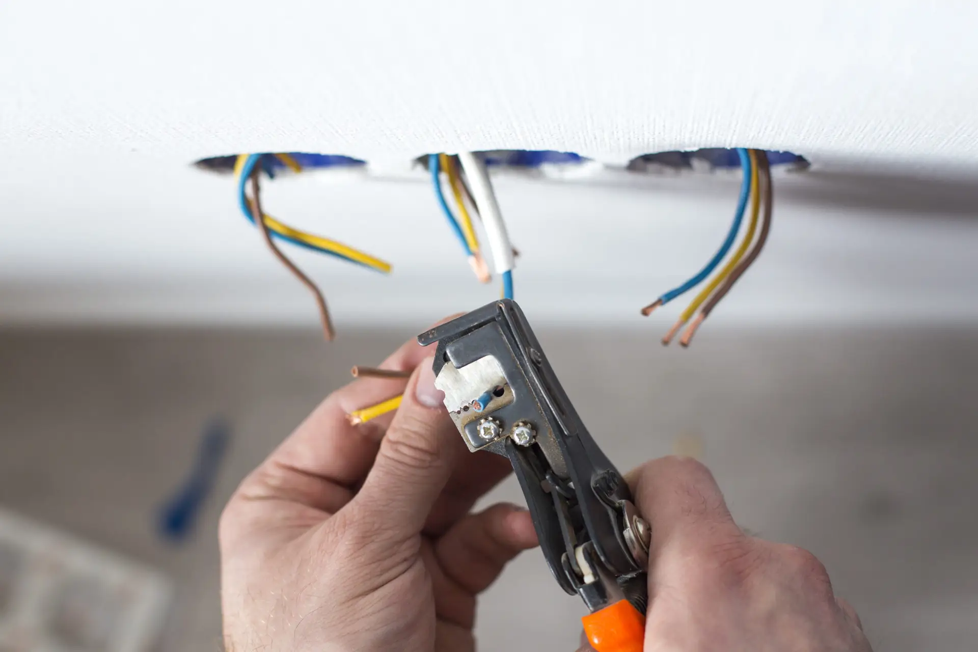 Electrician stripping insulation from wire for installation an electrical outlet in a Sheffield home